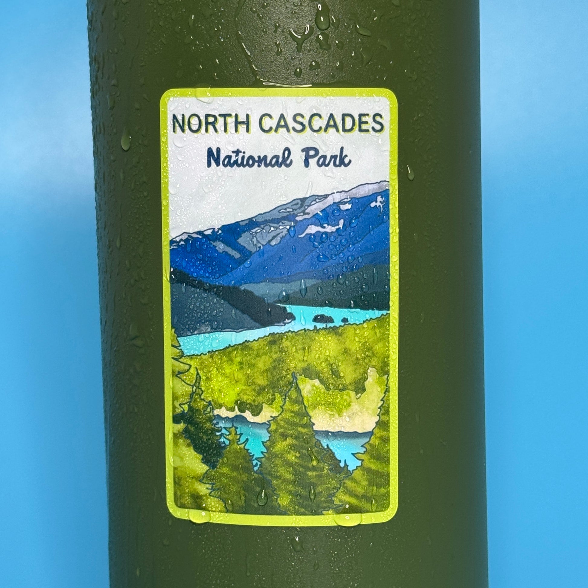 Sticker of North Cascades National Park on a green water bottle covered in water droplets.